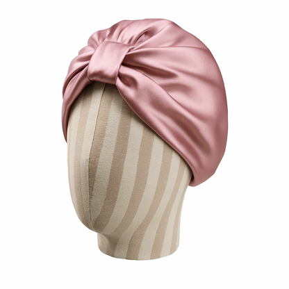 Pink satin turban on a mannequin head with a white background