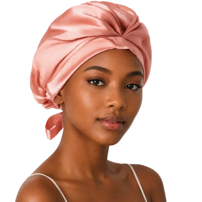 Woman wearing a pink satin headscarf on a plain background