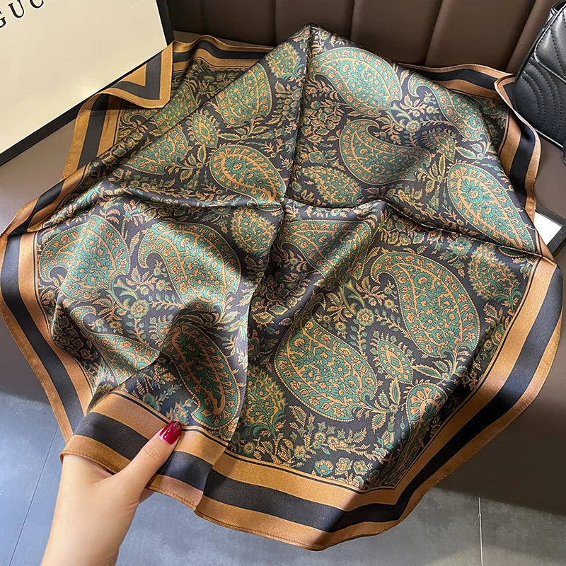 Decorative scarf with paisley pattern held by a hand on a neutral background