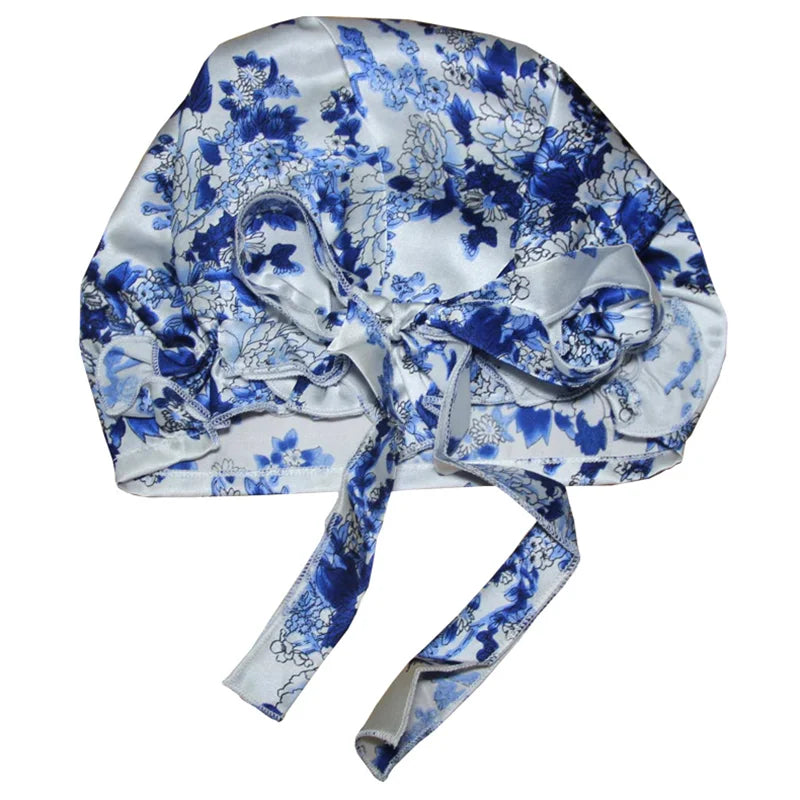 Blue floral satin bonnet with a bow, designed for luxurious hair protection during sleep, featuring a delicate floral pattern on satin fabric.