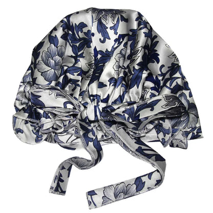 Blue and grey floral satin bonnet with a bow, designed for luxurious hair protection during sleep, featuring an elegant floral print on satin fabric.