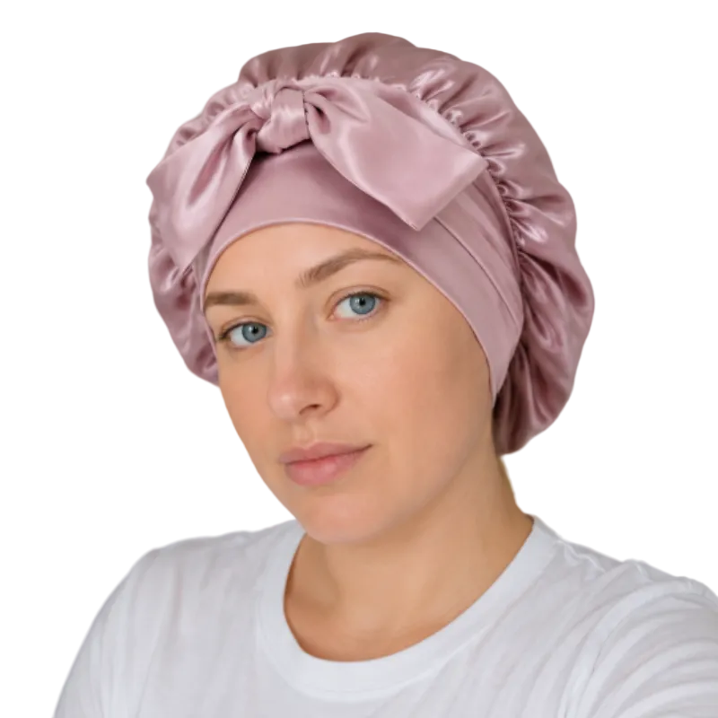 Woman wearing a pink satin headband with a bow in a neutral setting