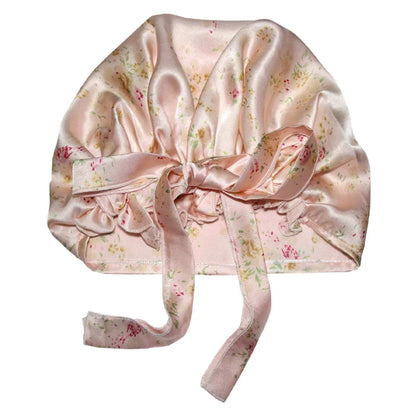 Pink floral satin bonnet with a bow, designed for hair protection and a luxurious sleep experience, featuring a delicate floral pattern on a soft satin fabric.