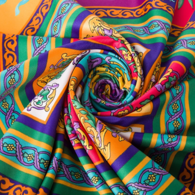 Luxury twill silk fabric close-up showing smooth shine and vivid bohemian patterns, Silkvana Amber Muse scarf.